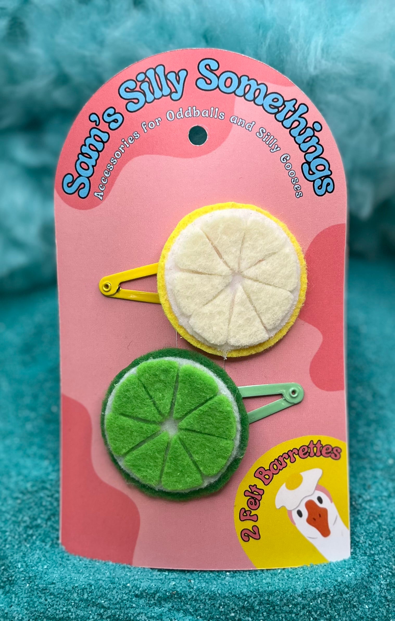 A pack of two handmade barrettes, one designed to resemble a lemon and the other like a lime, placed on a pink card with the text 'Sam's Silly Something'.