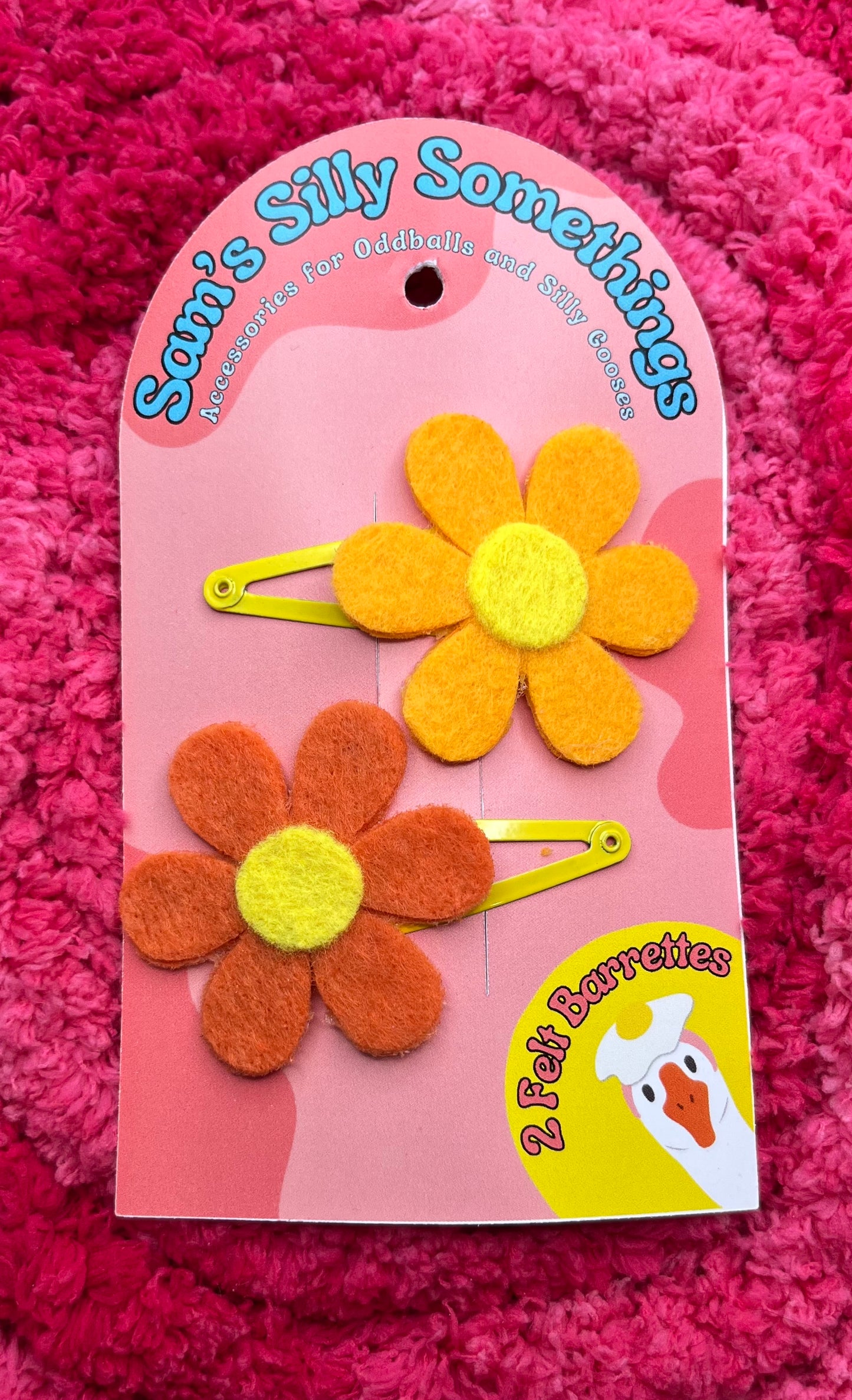 Flower-shaped hair accessories on a pink card with 'Sam's Silly Somethings' branding on a pink textured background.