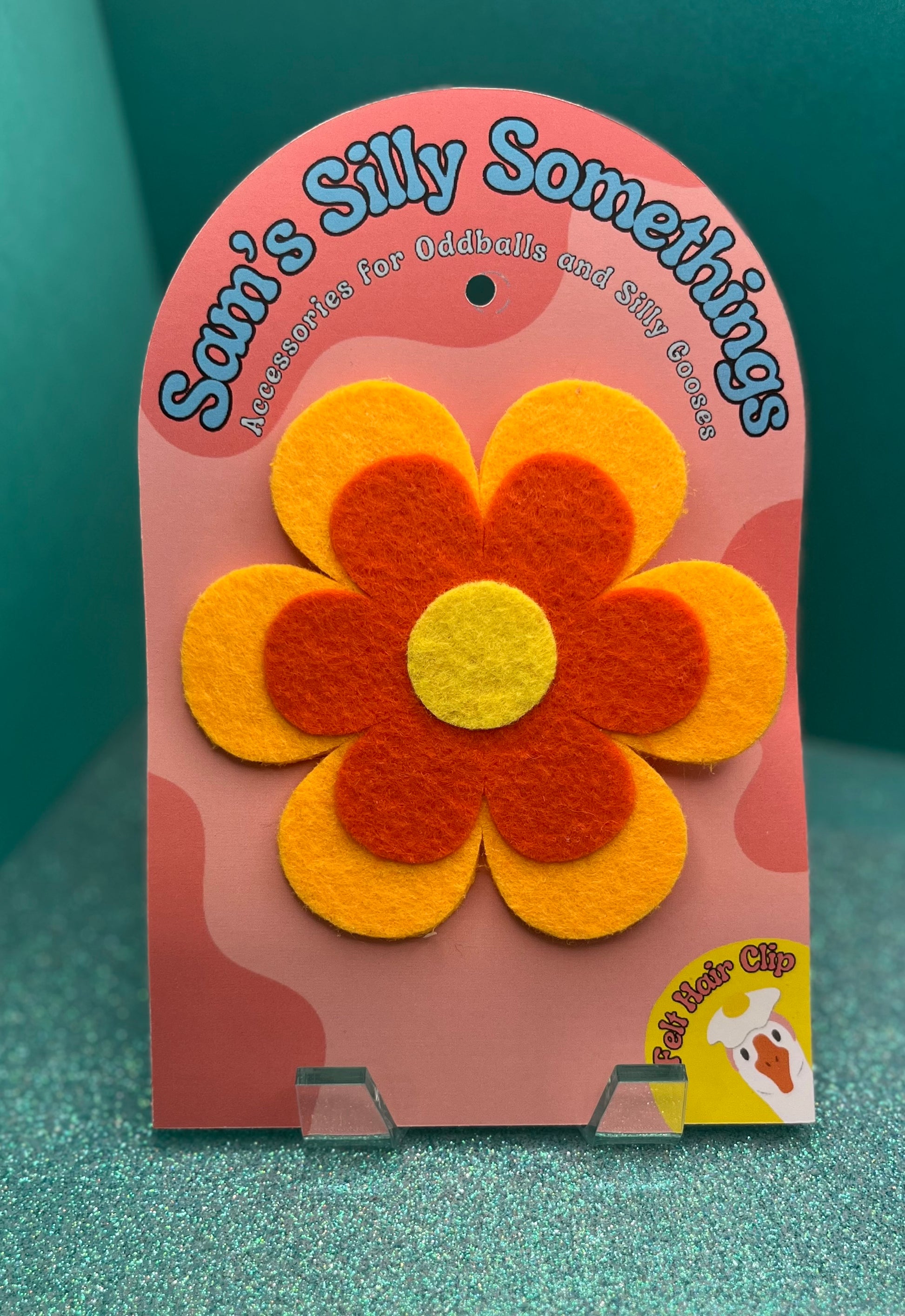 Flower-shaped hair clip on a 'Sam's Silly Something' branded card against a green background
