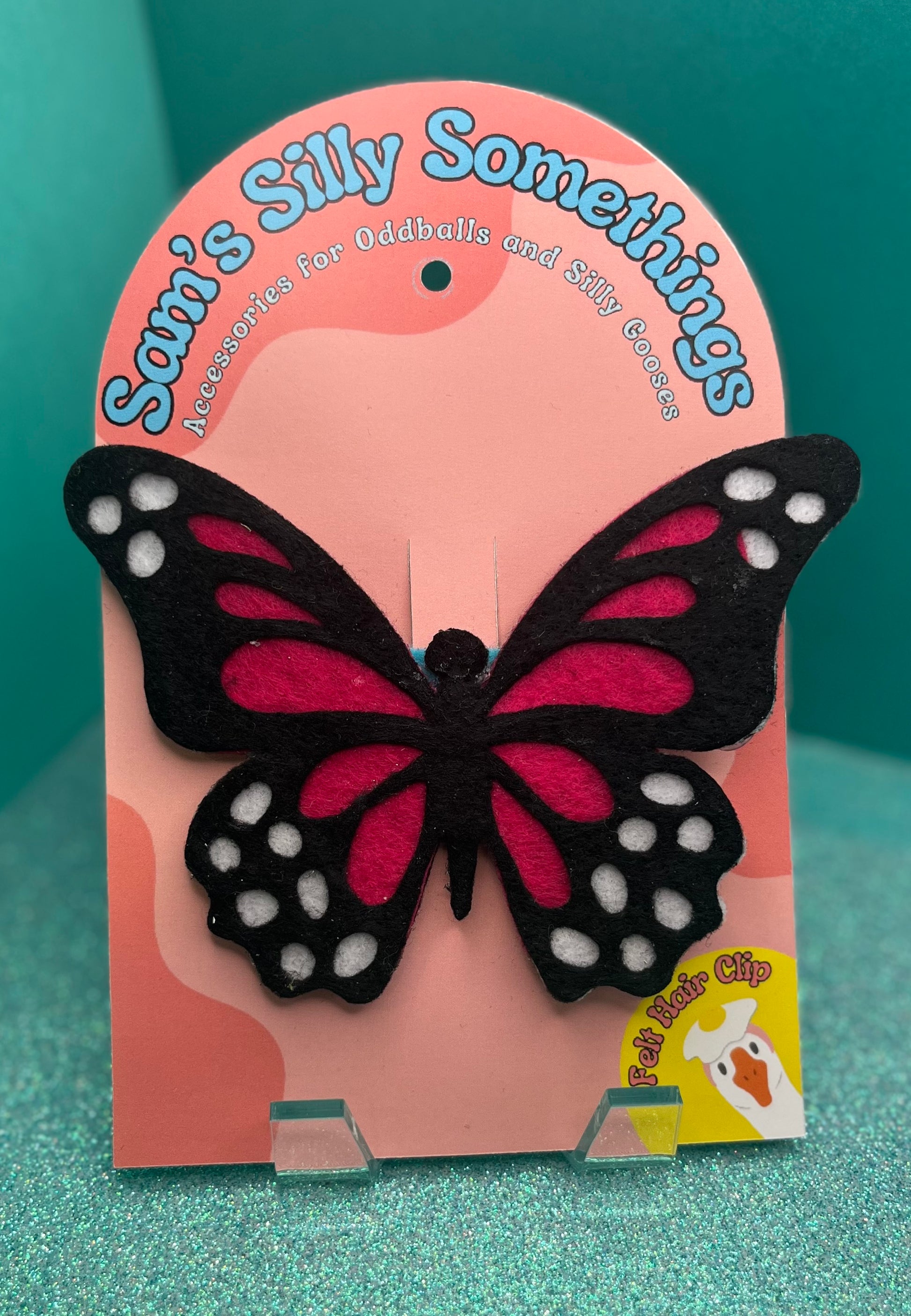 Butterfly hair clip in packaging with 'Sam's Silly Somethings' branding on a teal background